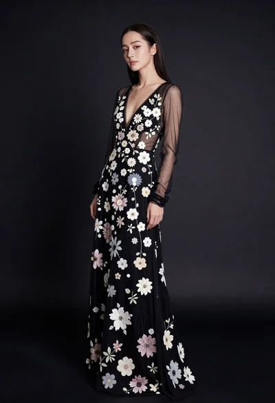 Full body portrait of woman in embellished black gown against dark studio