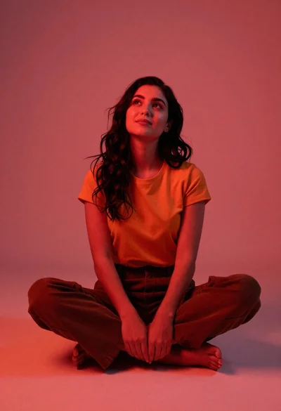 Young woman sitting on floor in red and orange light