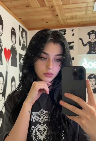Young woman taking mirror selfie in room with stencil art and neon