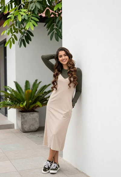 Young woman in slip dress leaning on white wall in courtyard