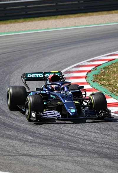 Dark blue formula one race car speeding around a curve on asphalt