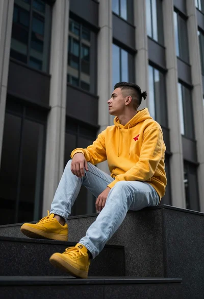 Young man sitting on dark ledge in modern urban setting low angle