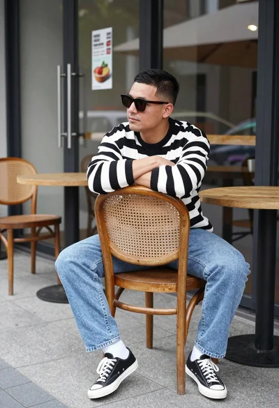 Man sitting casually on wooden chair outside glass cafe patio area