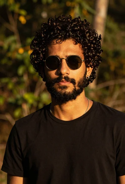 Closeup portrait of young man with dark curly hair and beard wearing