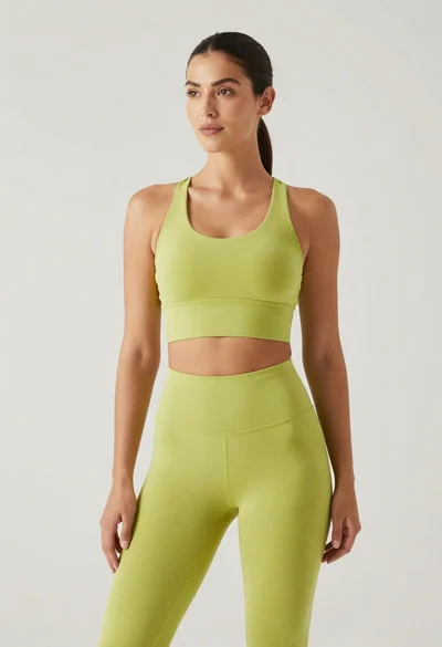 Fit woman in lime green athletic outfit standing in a studio